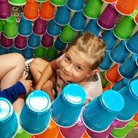 Child sitting among colorful plastic cups