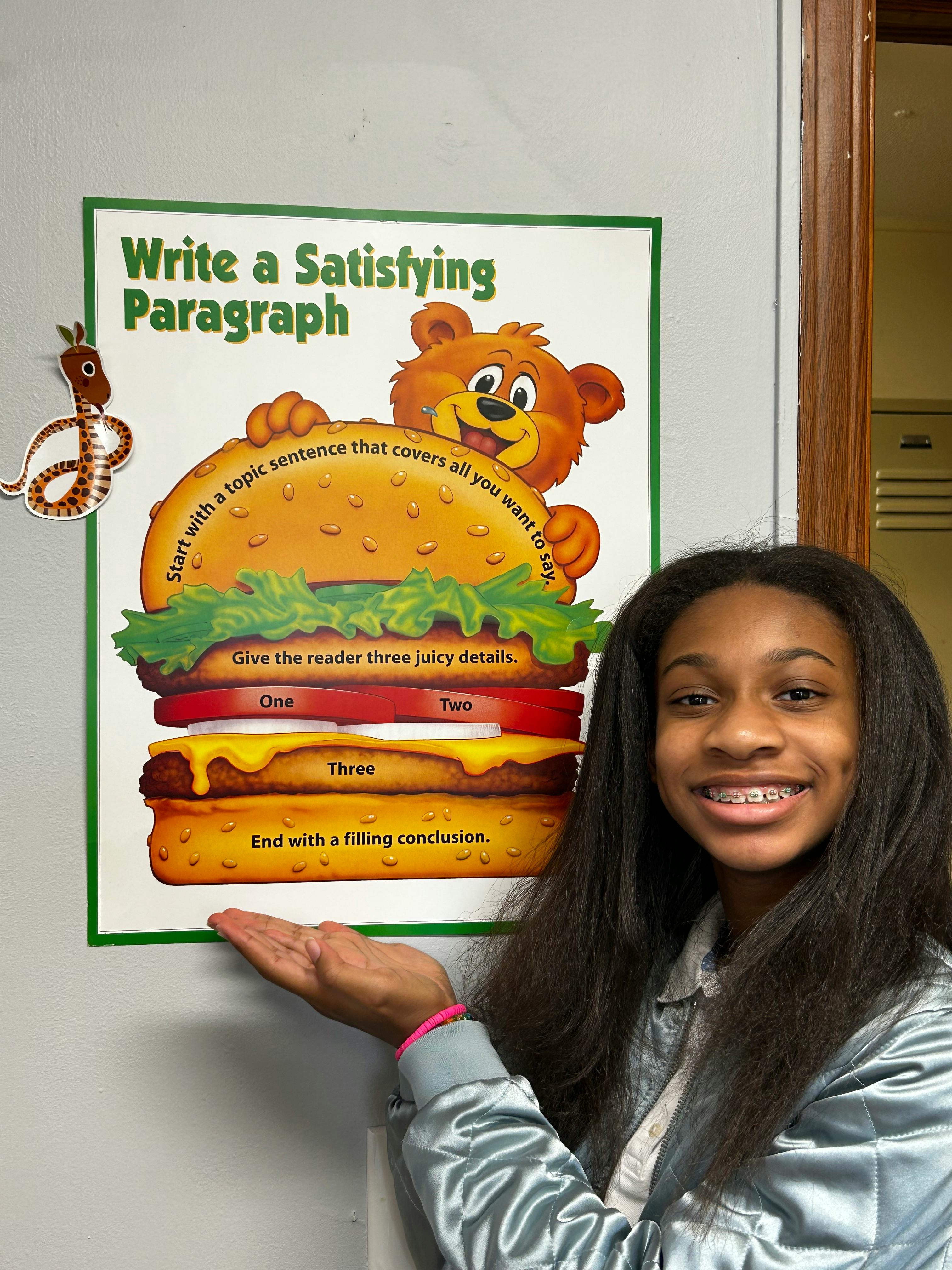 Teen standing next to a poster about writing a satisfying paragraph