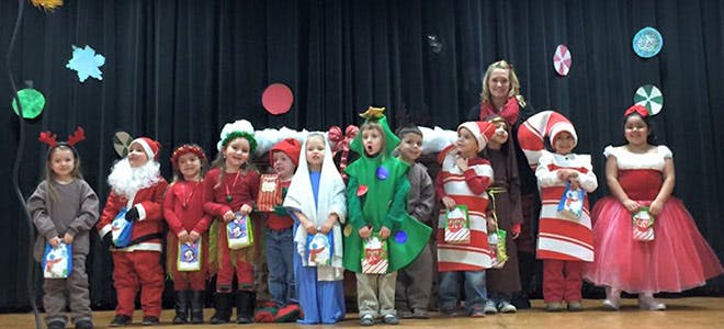 Children and an adult in holiday costumes on a stage
