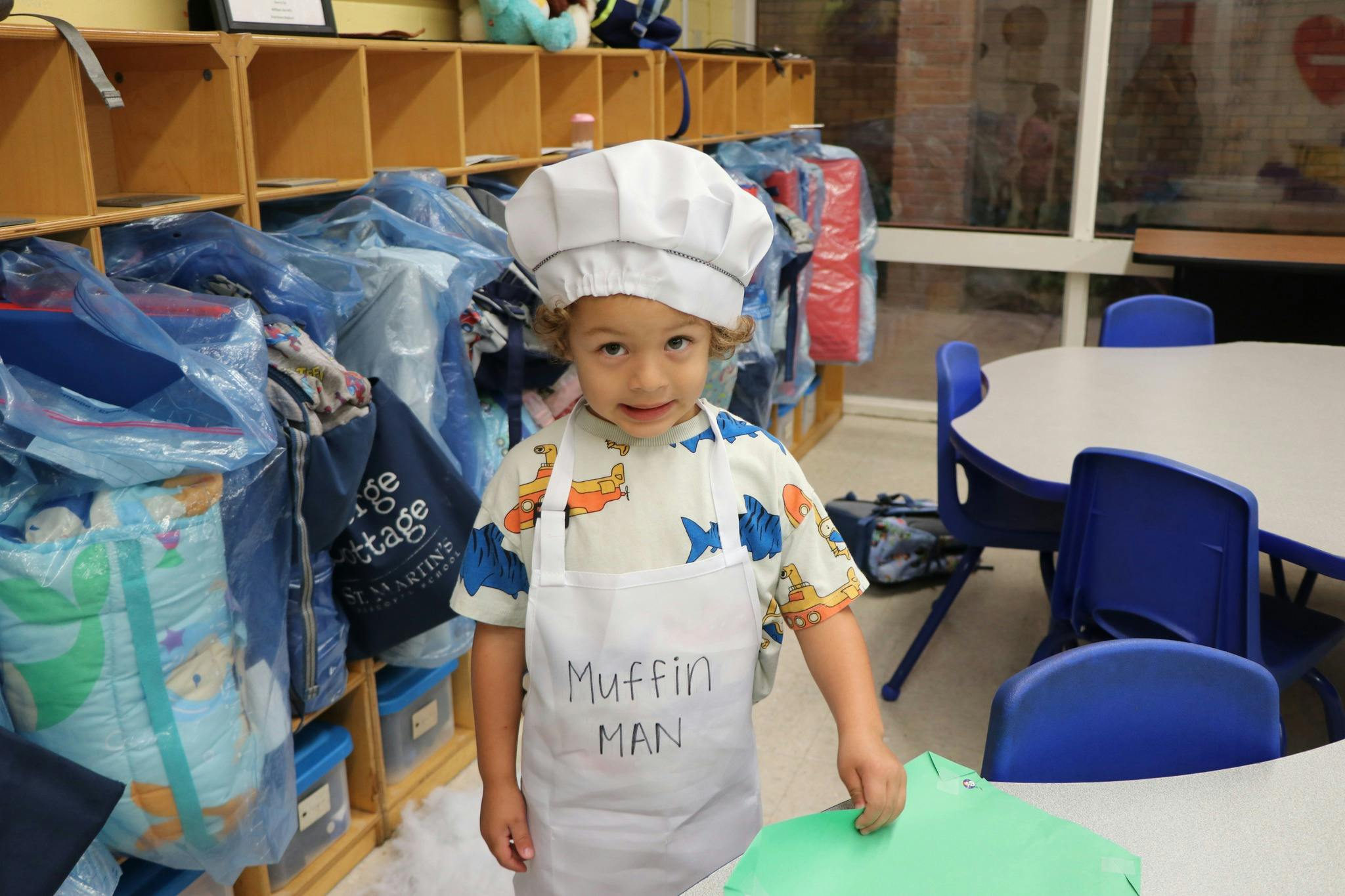 Child in a chef hat and apron with "Muffin Man" written on it