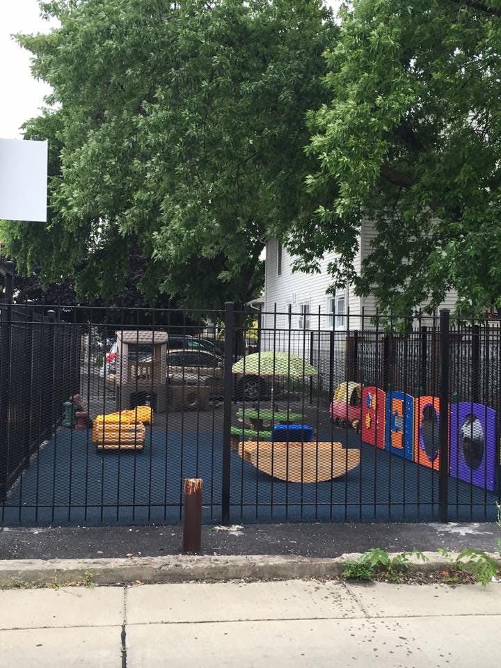 Playground with colorful play structures behind a black fence