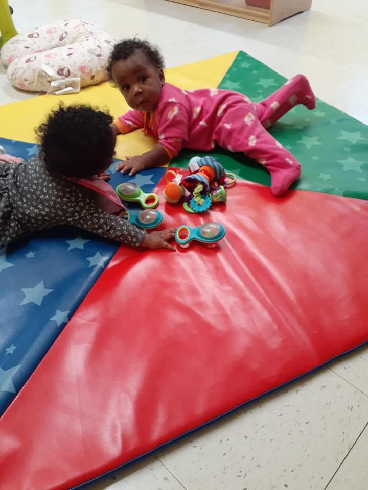 Two children playing with toys on a colorful mat
