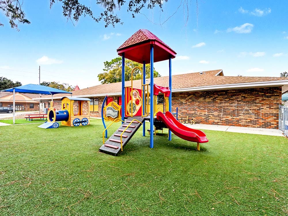 Playground with a slide, climbing structure, and train-shaped tunnel