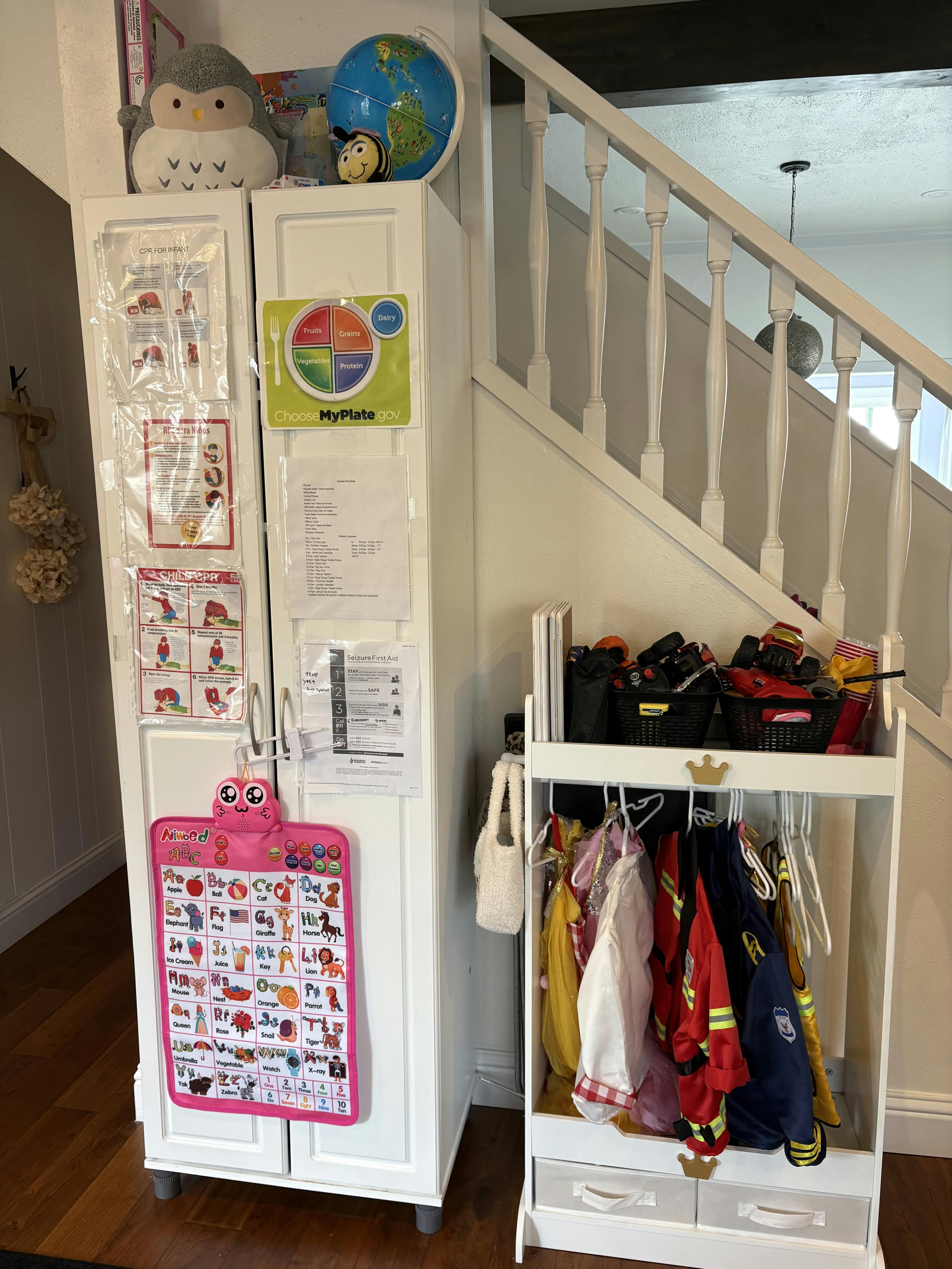 White storage cabinet with educational charts and a dress-up clothes rack