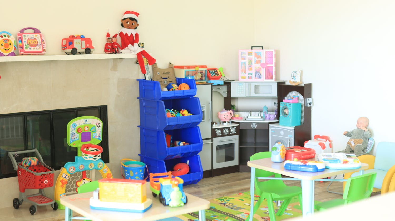 Playroom with children's toys including a play kitchen, basketball hoop, and bins