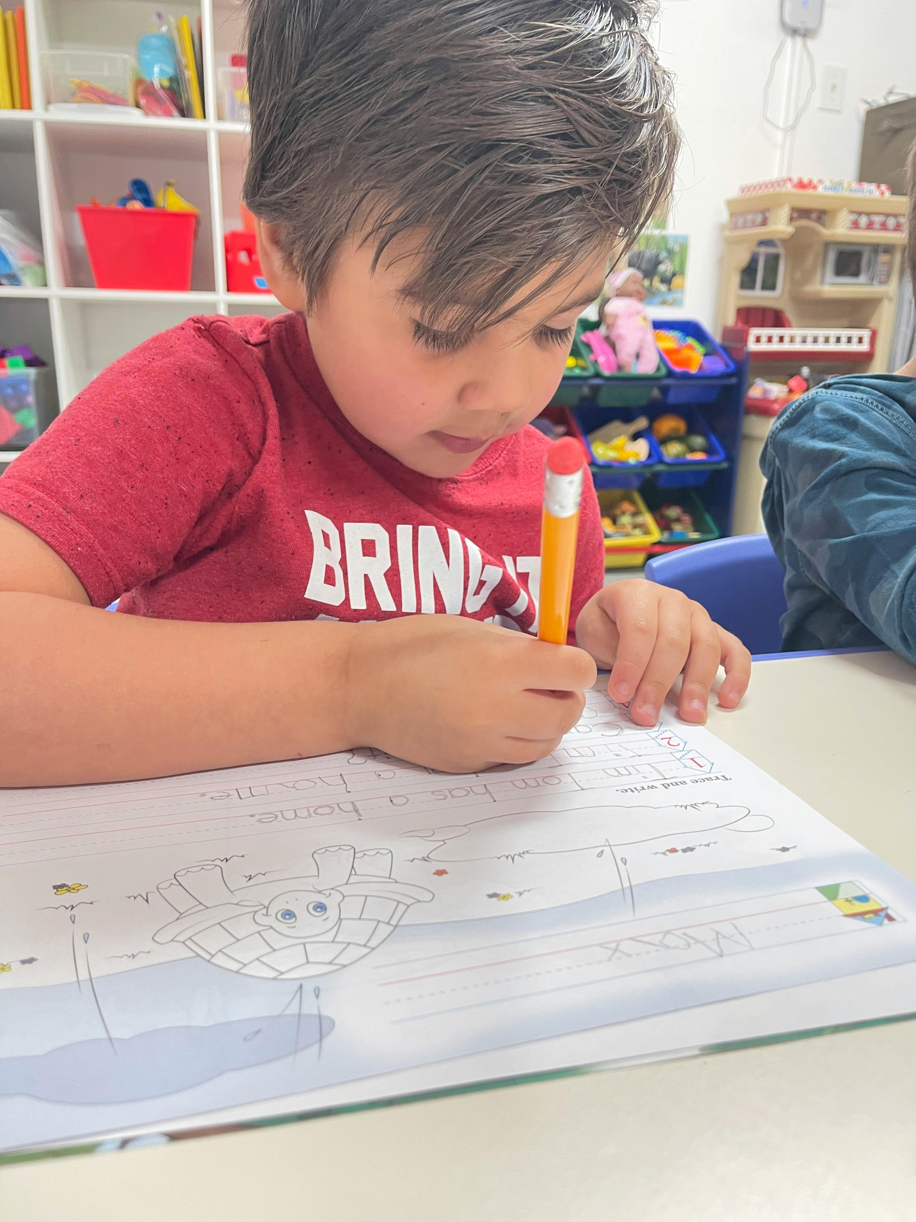 Child drawing in a book with a pencil