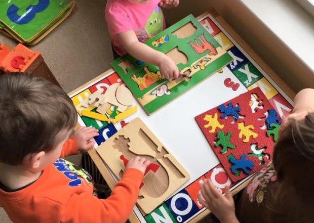 Children playing with wooden puzzles at a table