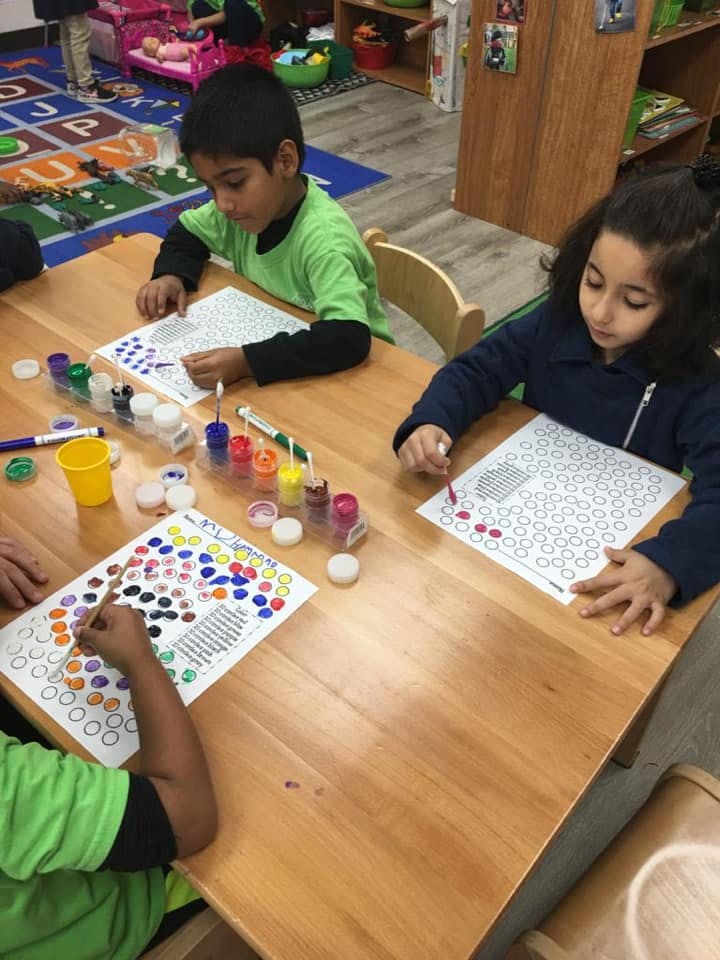 Children painting dot art at a table