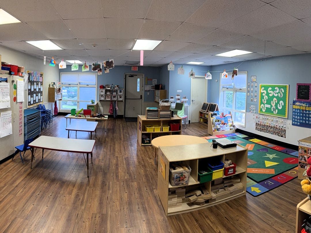 Empty classroom with small tables and a colorful rug