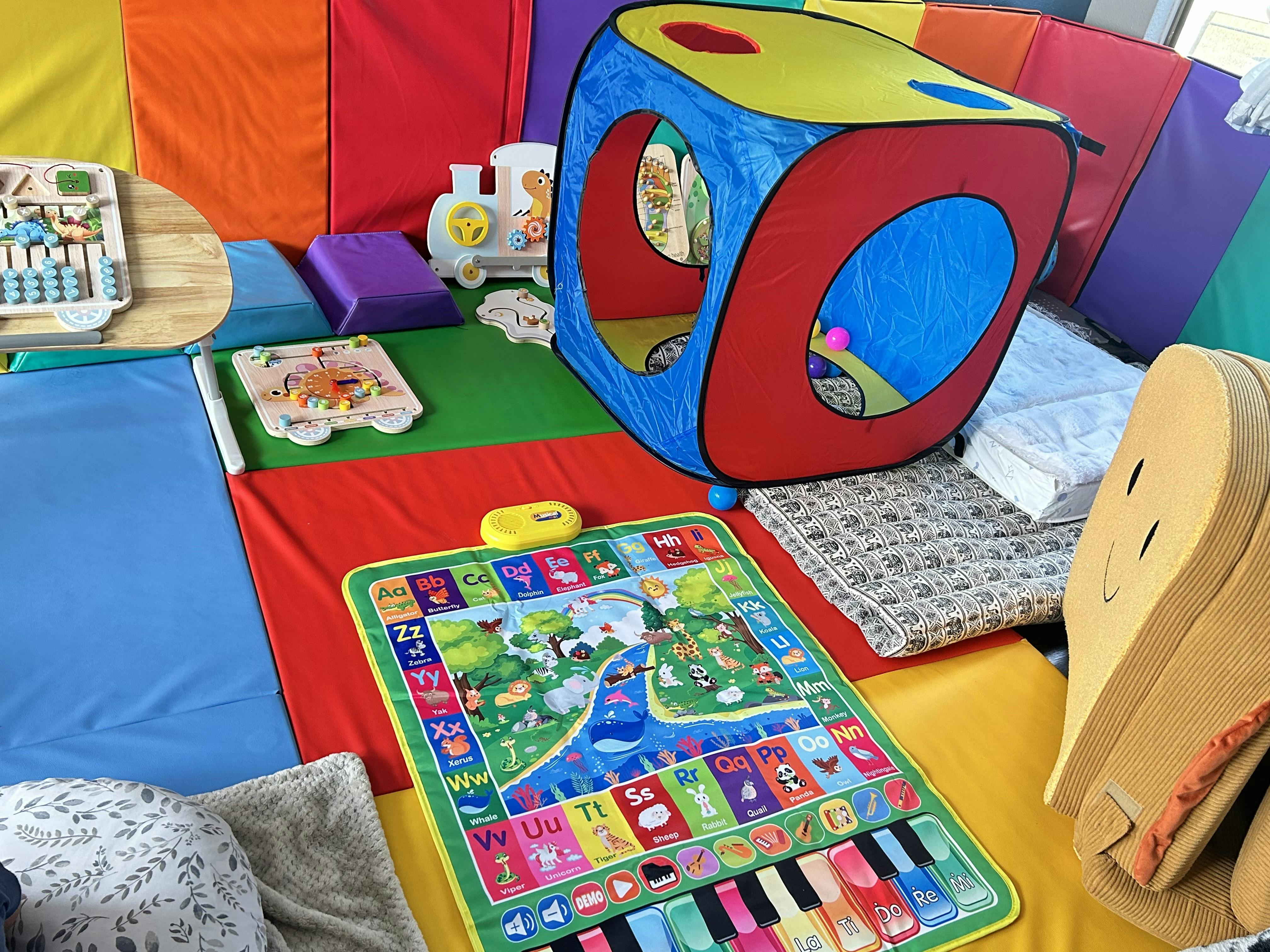Colorful playroom with a toy tunnel, alphabet floor mat, and wooden toys