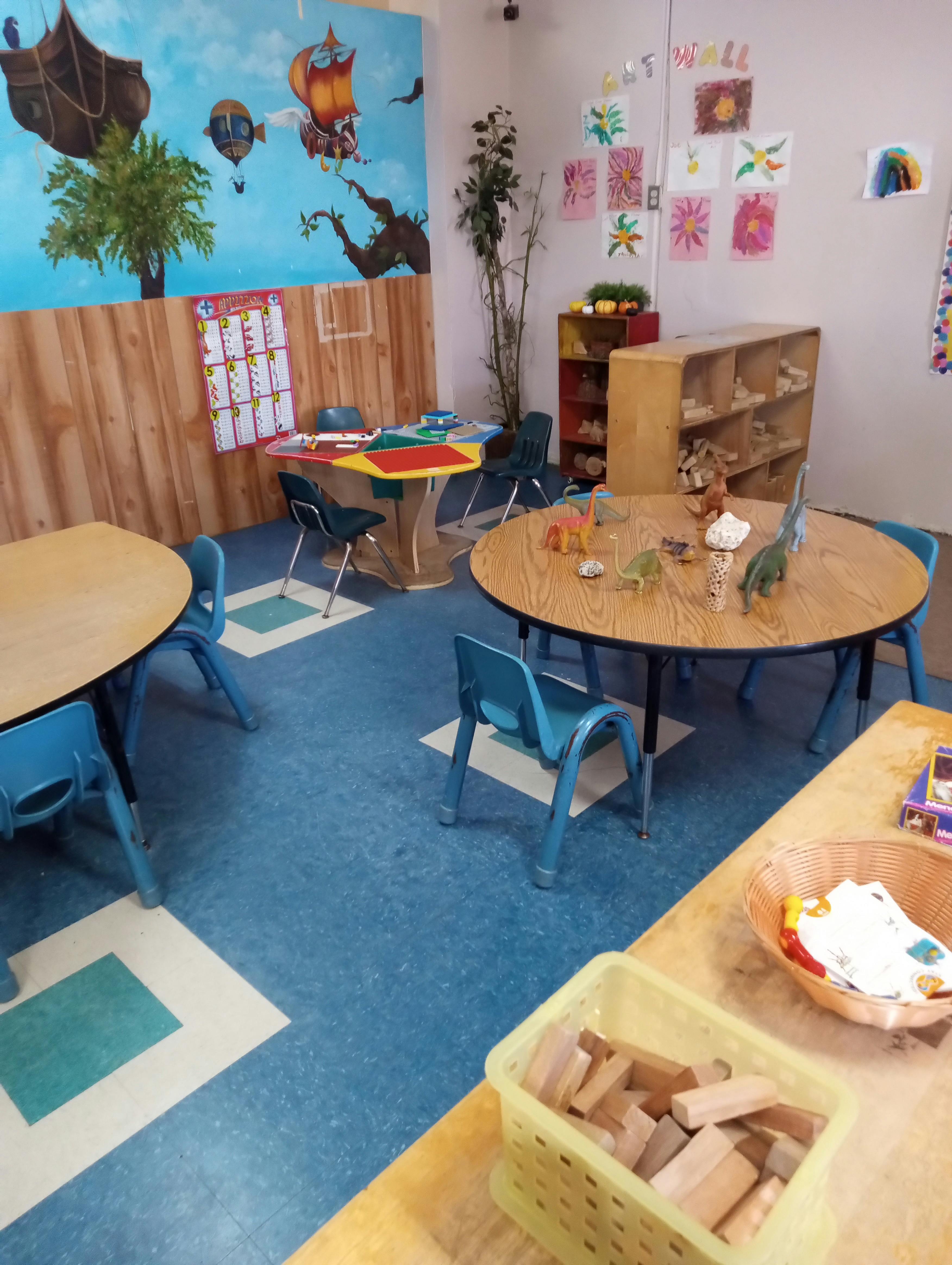Classroom with child-sized tables and chairs, wall art, and toys