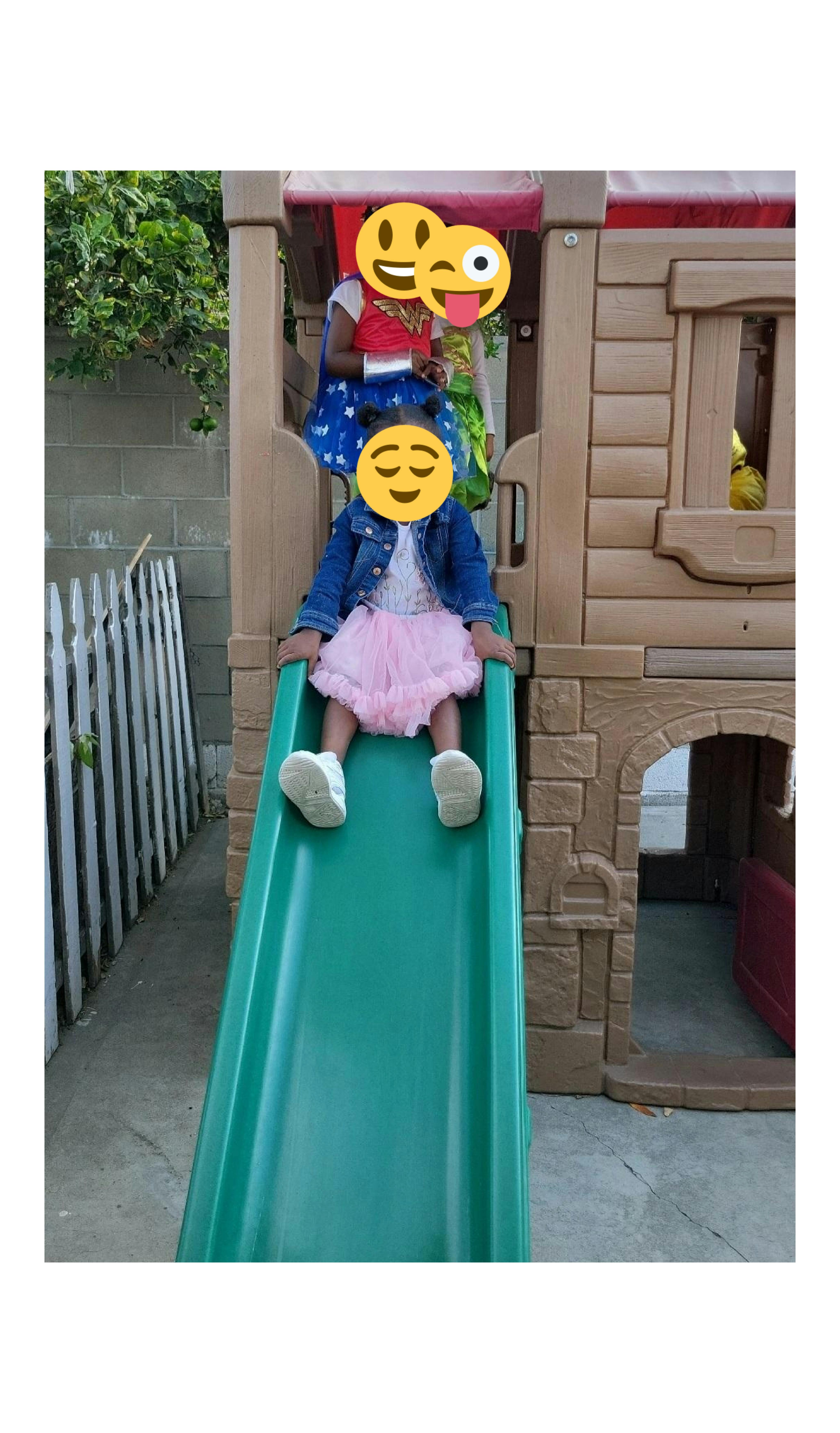 Two children on a playground slide and play structure
