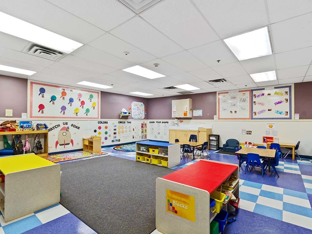 An empty childcare classroom with small tables and chairs