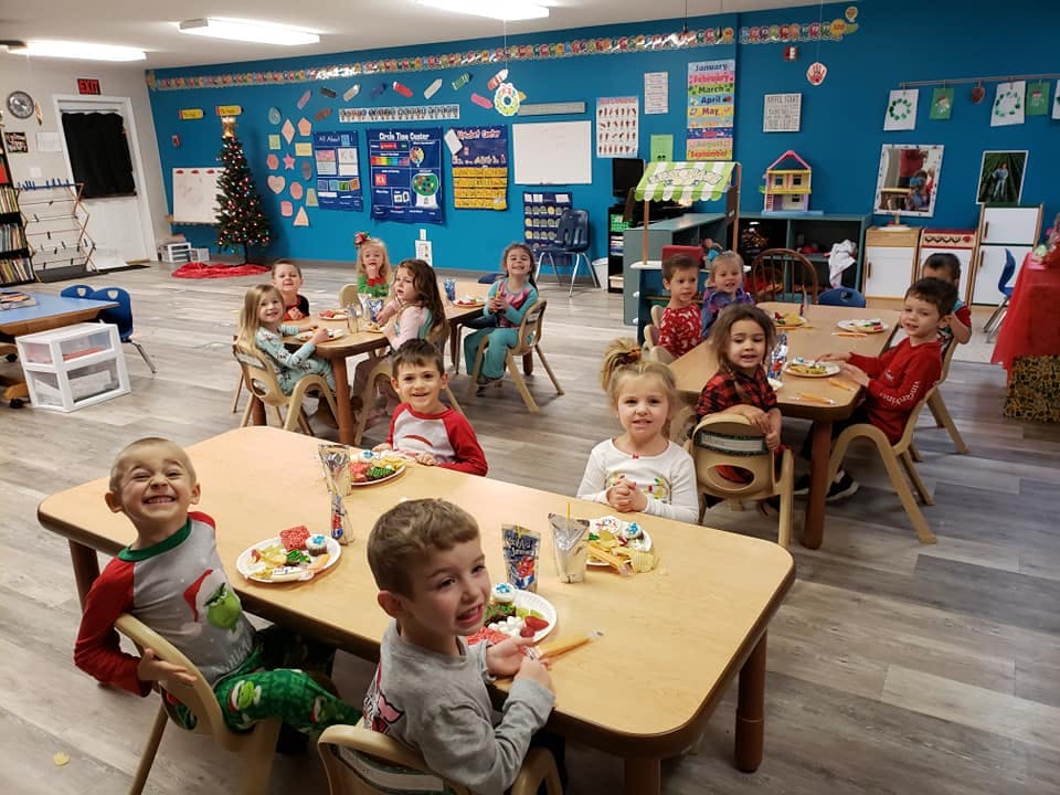 Children sitting at tables in a classroom eating snacks