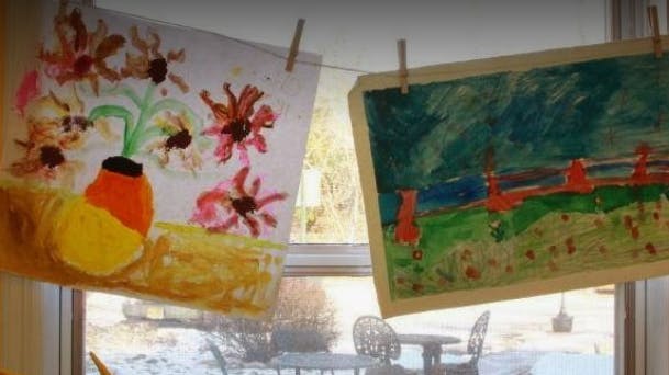 Two child drawings hanging on a string with clothespins