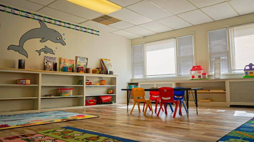 Classroom with small chairs and tables, shelves with items, and dolphin wall art