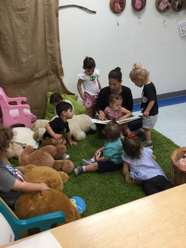 Adult reading a book to several children in a classroom
