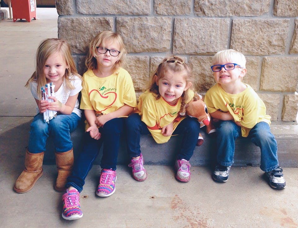 Four children sitting on a ledge