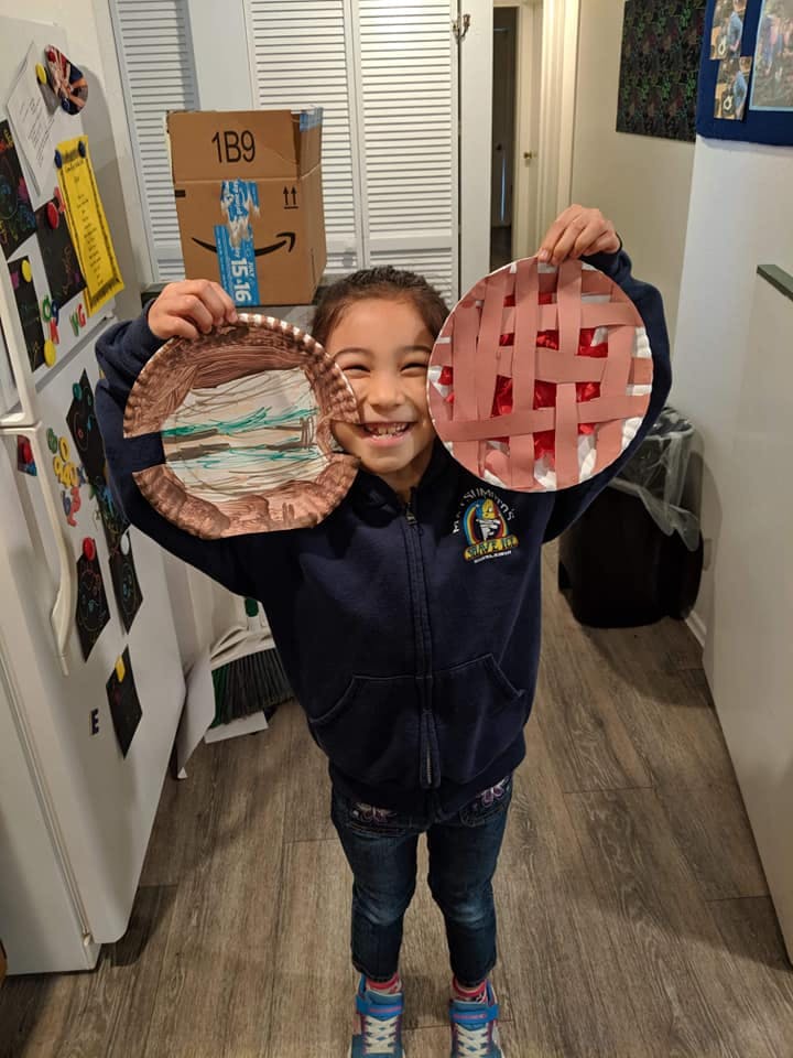 Child holding up two paper plate crafts