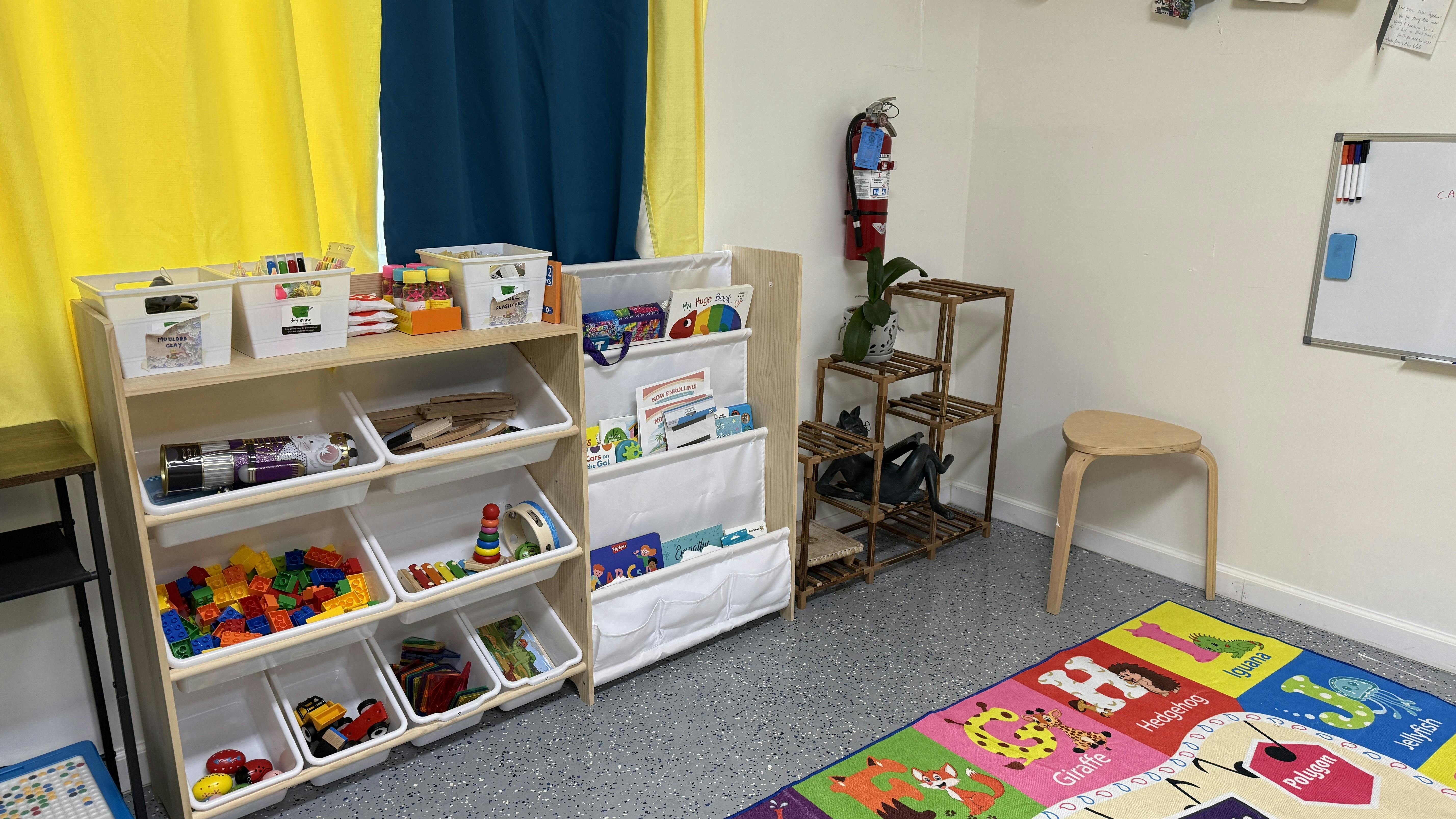 Classroom with toy shelves, book display, and alphabet rug
