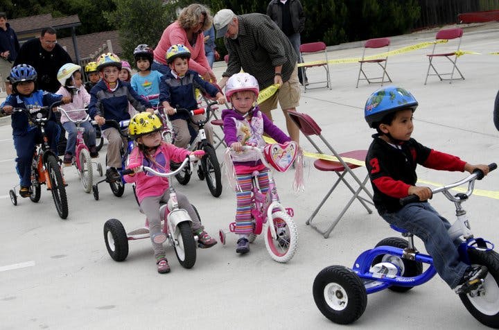Children on bicycles and tricycles with adults nearby
