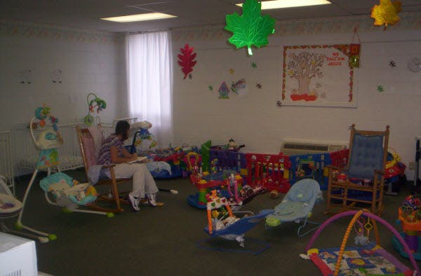 Person sitting in a room with baby swings and play mats