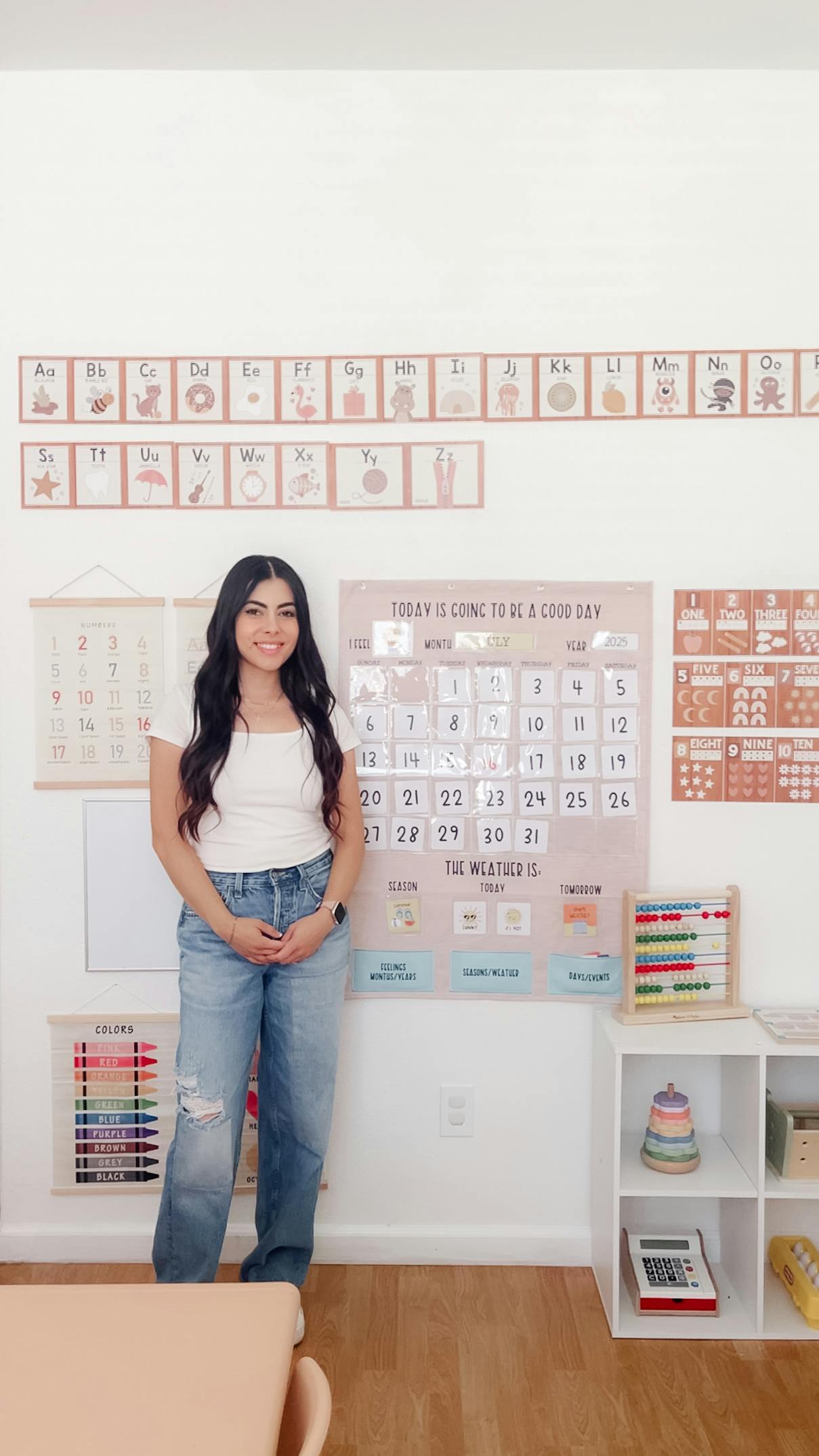 Person standing in a classroom with alphabet and calendar displays