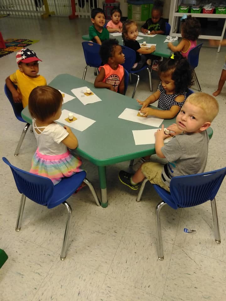 Children sitting at small tables in a classroom