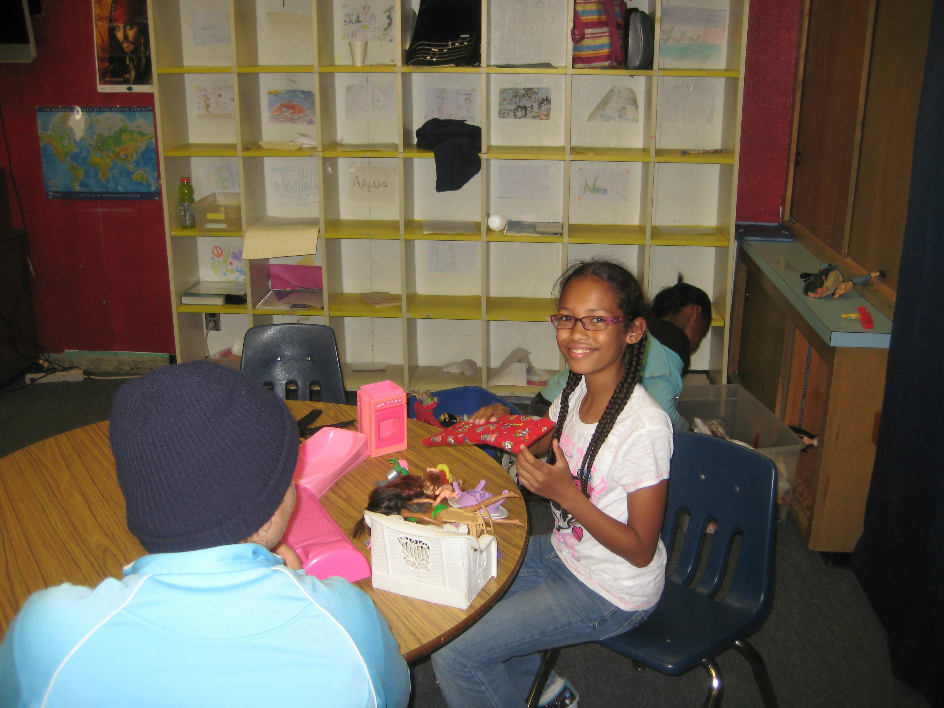 Teen in glasses smiling at a table with another person