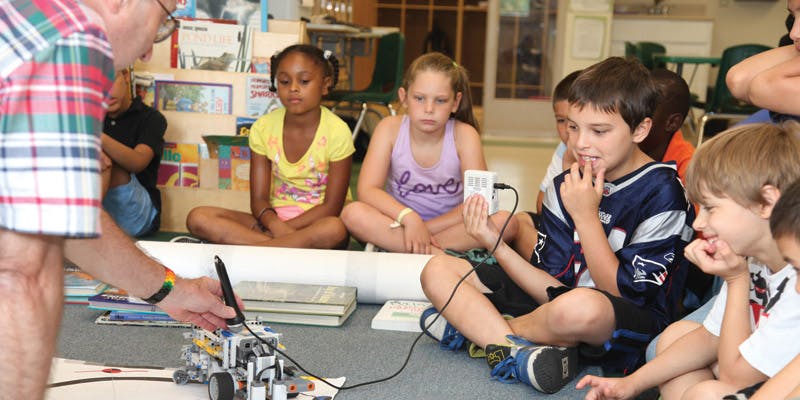 Adult and children observing a small robot