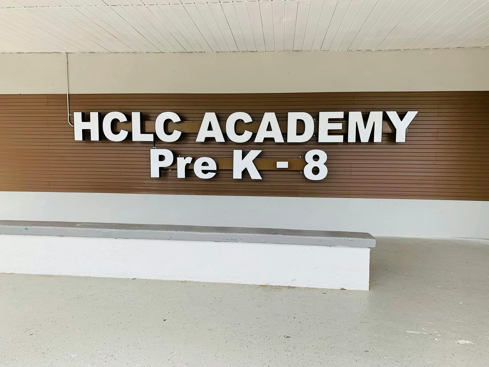 HCLC Academy Pre K-8 sign on a brown wall
