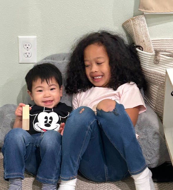 Two children sitting together, one holding a wooden block