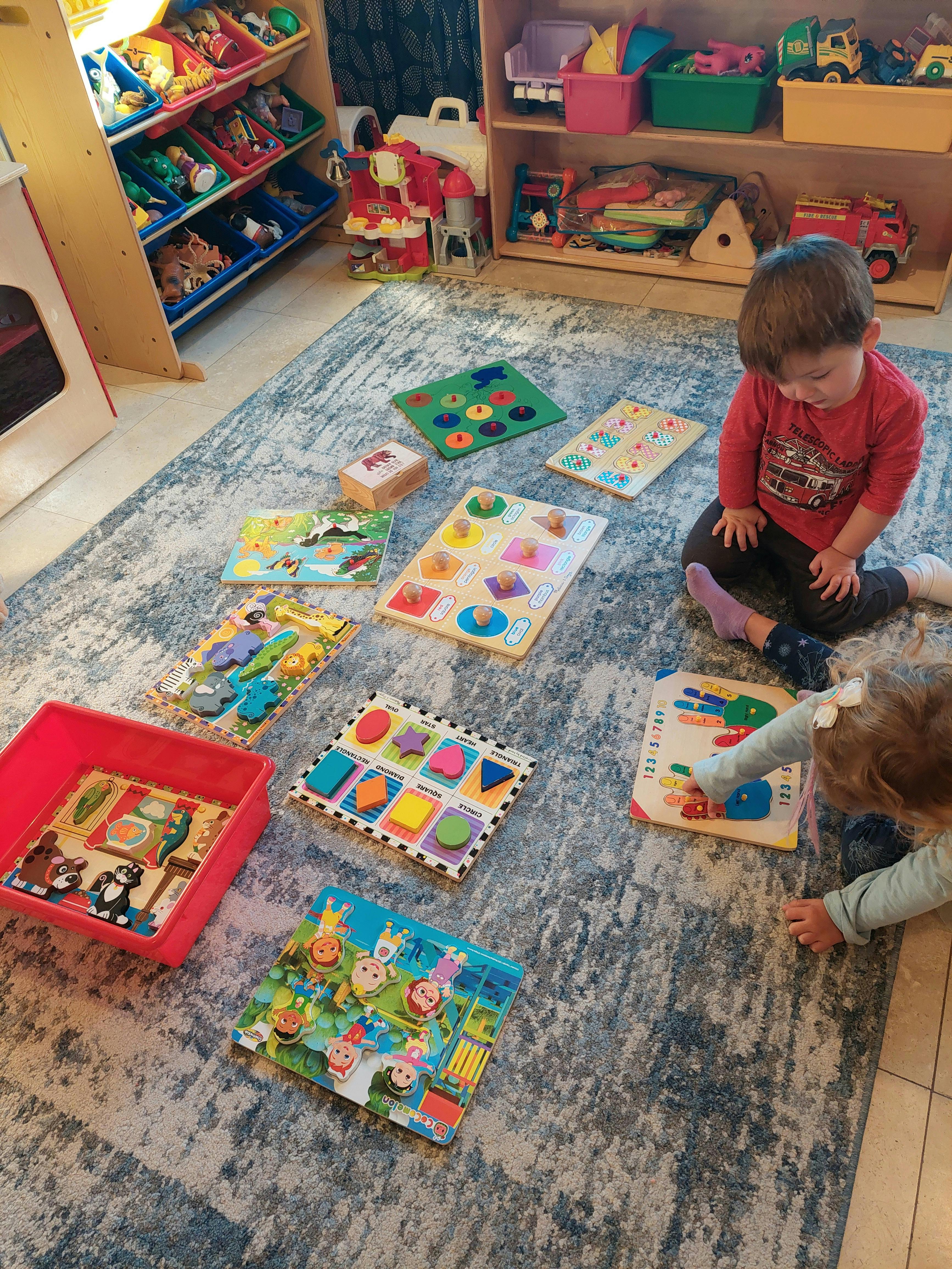 Two children playing with puzzles on a rug