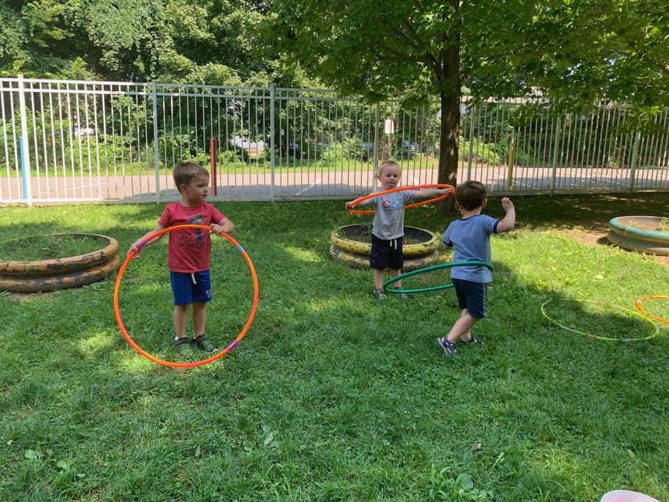 Three children playing with hula hoops outdoors