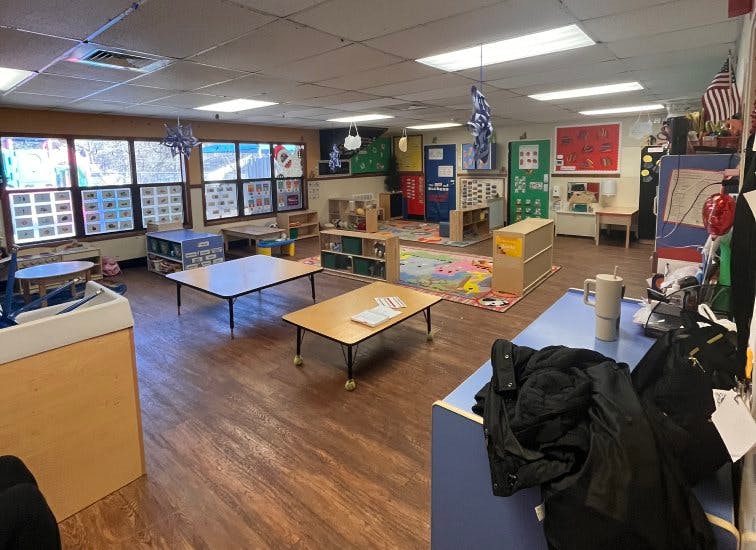 An empty classroom with multiple tables and colorful decorations