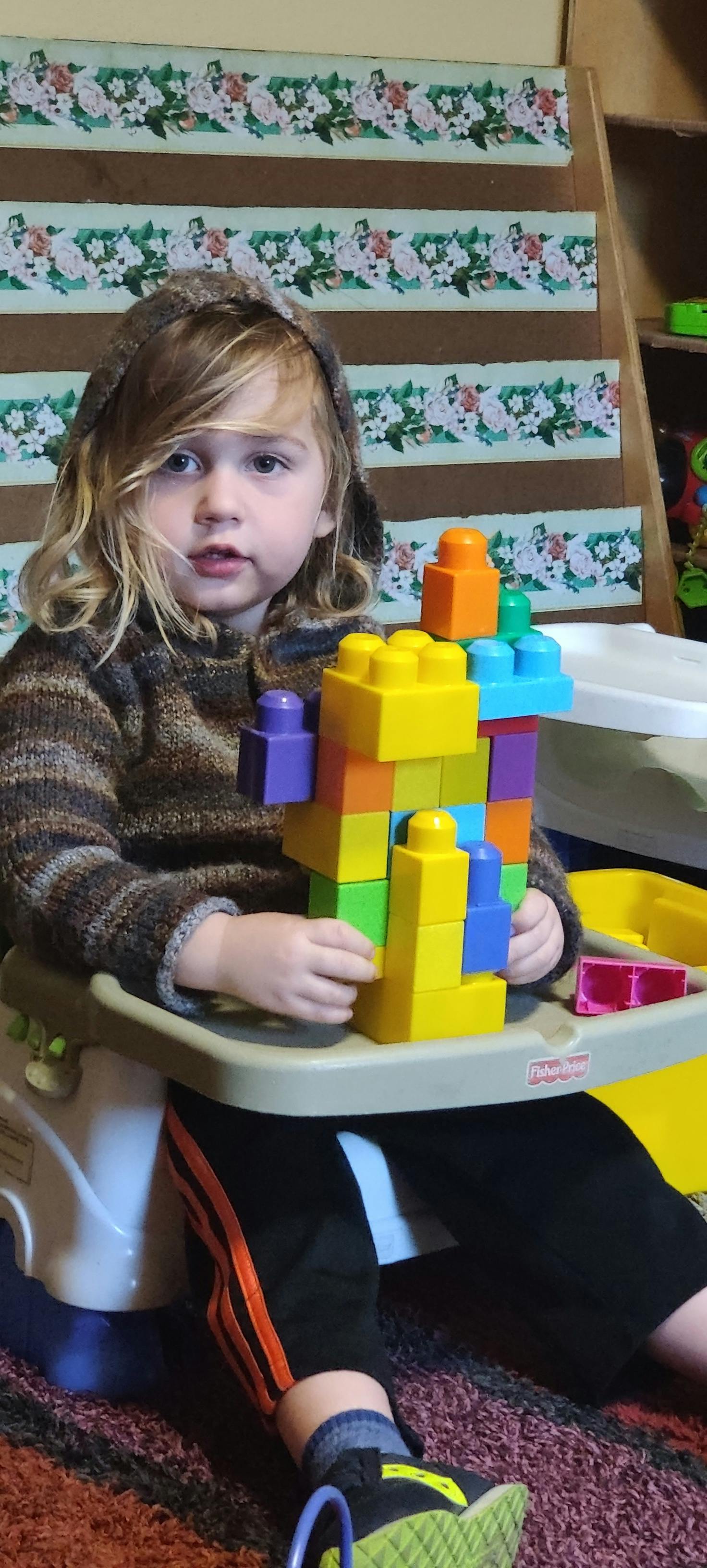 Child in a high chair playing with colorful building blocks
