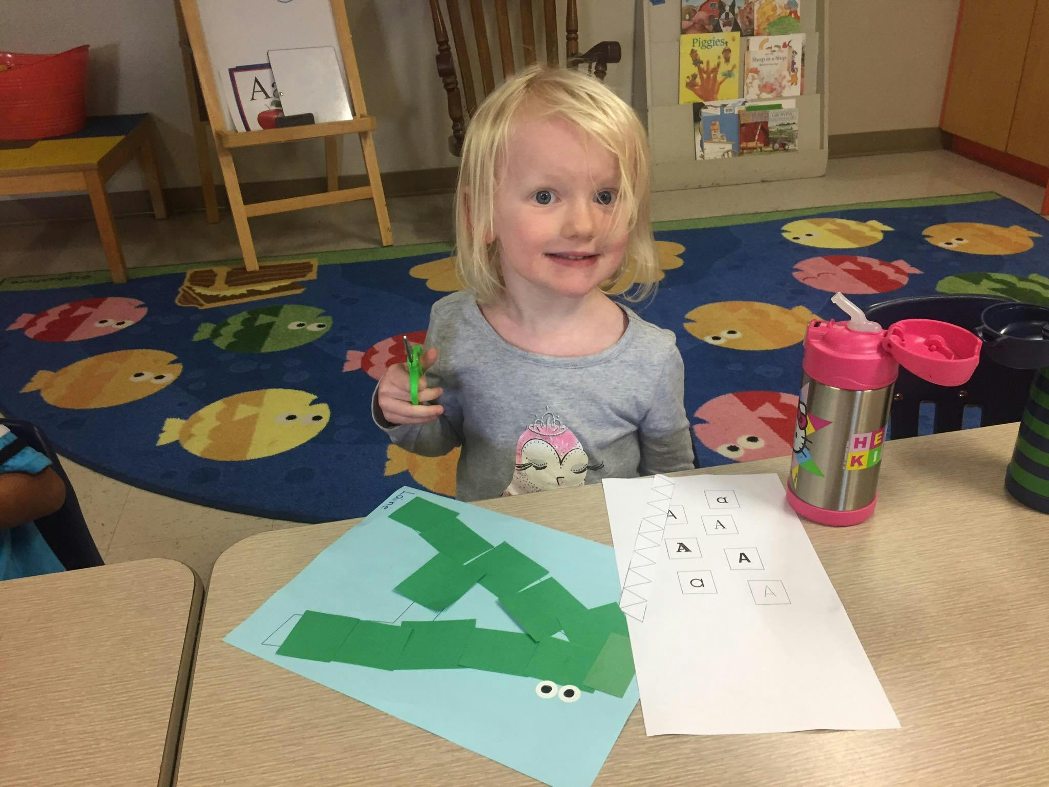 Child at a table with craft supplies and a drink bottle