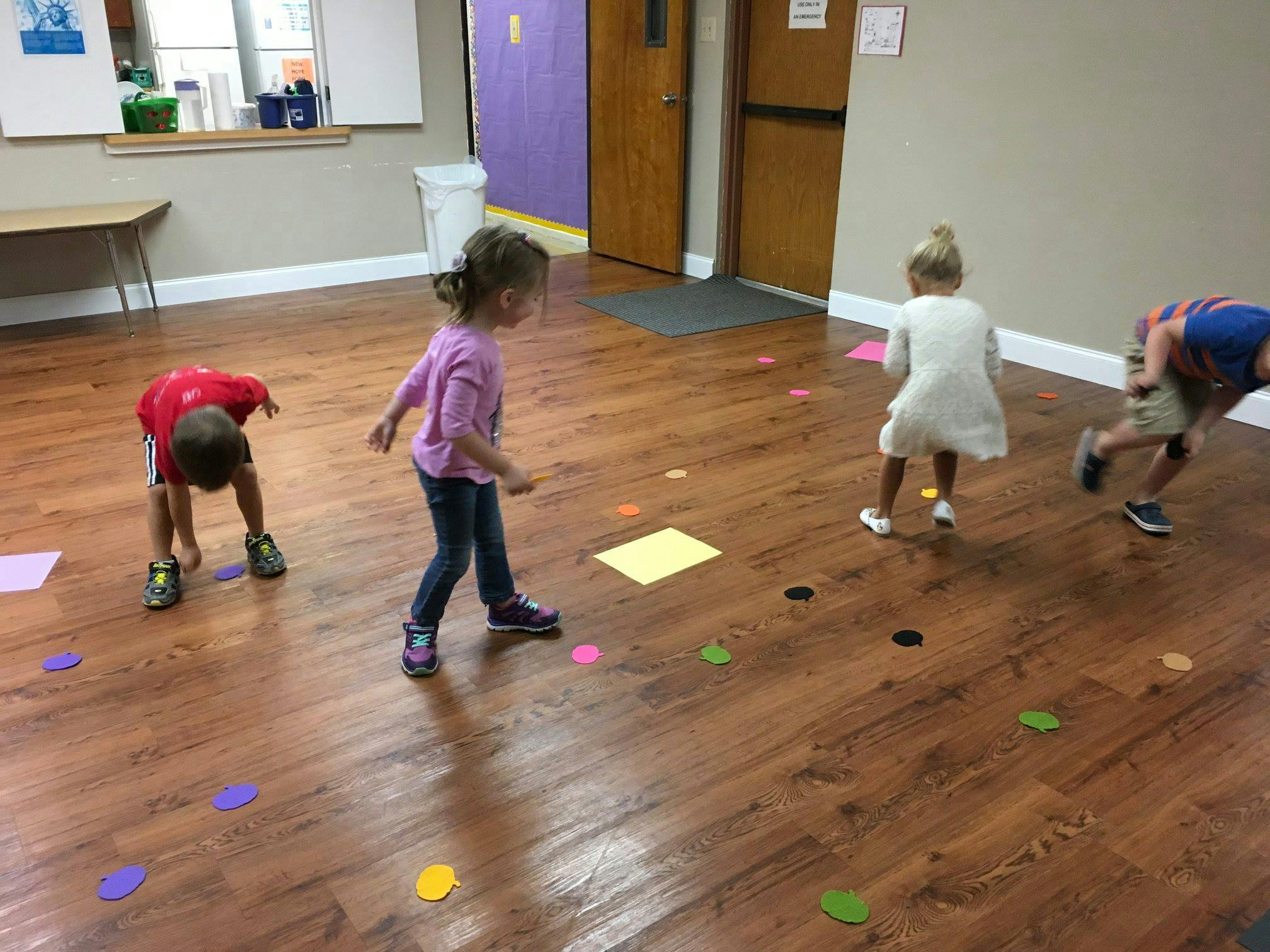 Children playing on a wooden floor with colorful shapes