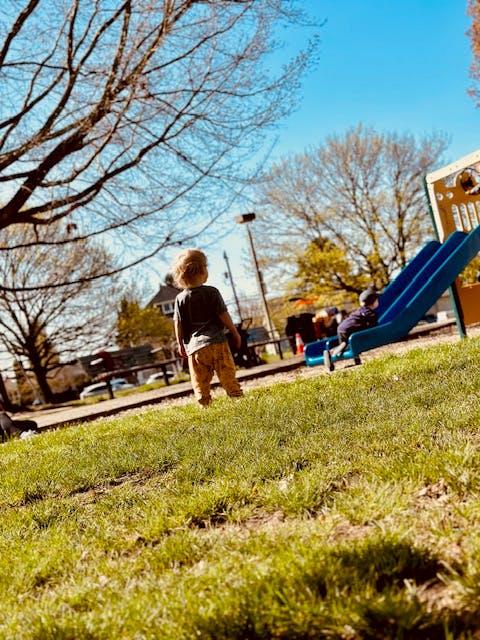 Child standing on grass in a playground