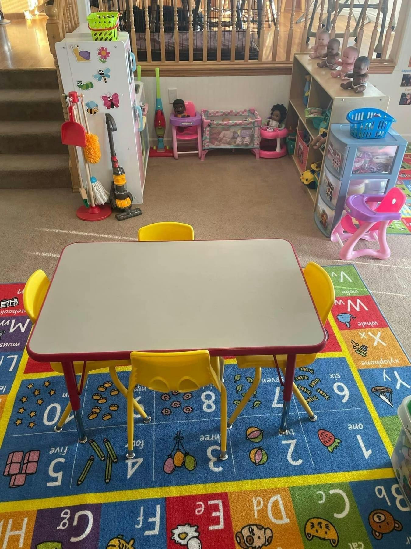 Child-sized table and chairs on an alphabet and numbers rug in a playroom