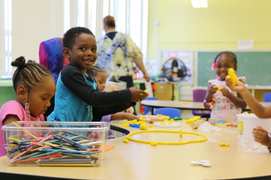 Children playing with colorful objects at a table in a classroom