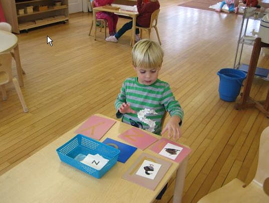 Child at a table with cards and a blue basket