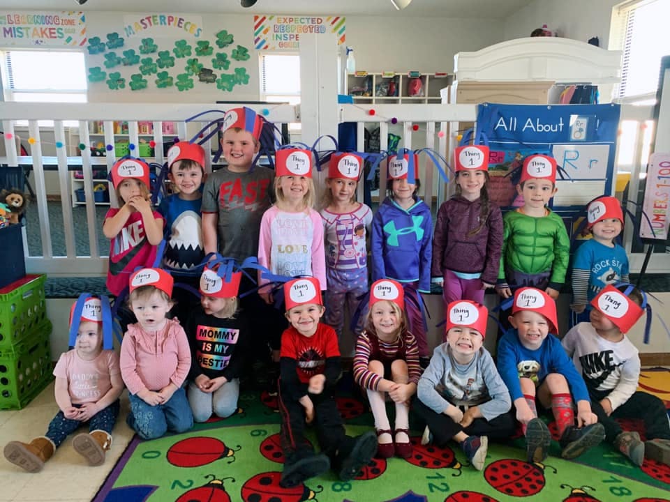Group of children wearing red hats in a classroom