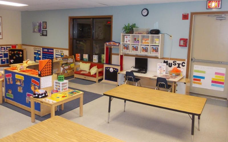 An empty early childhood classroom with activity centers and small tables