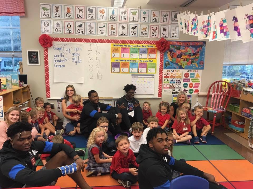 Adults and children sitting on a classroom floor