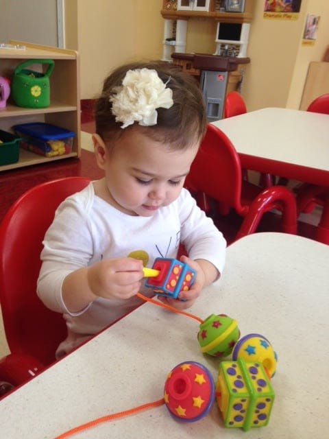 Child playing with a lacing toy at a table