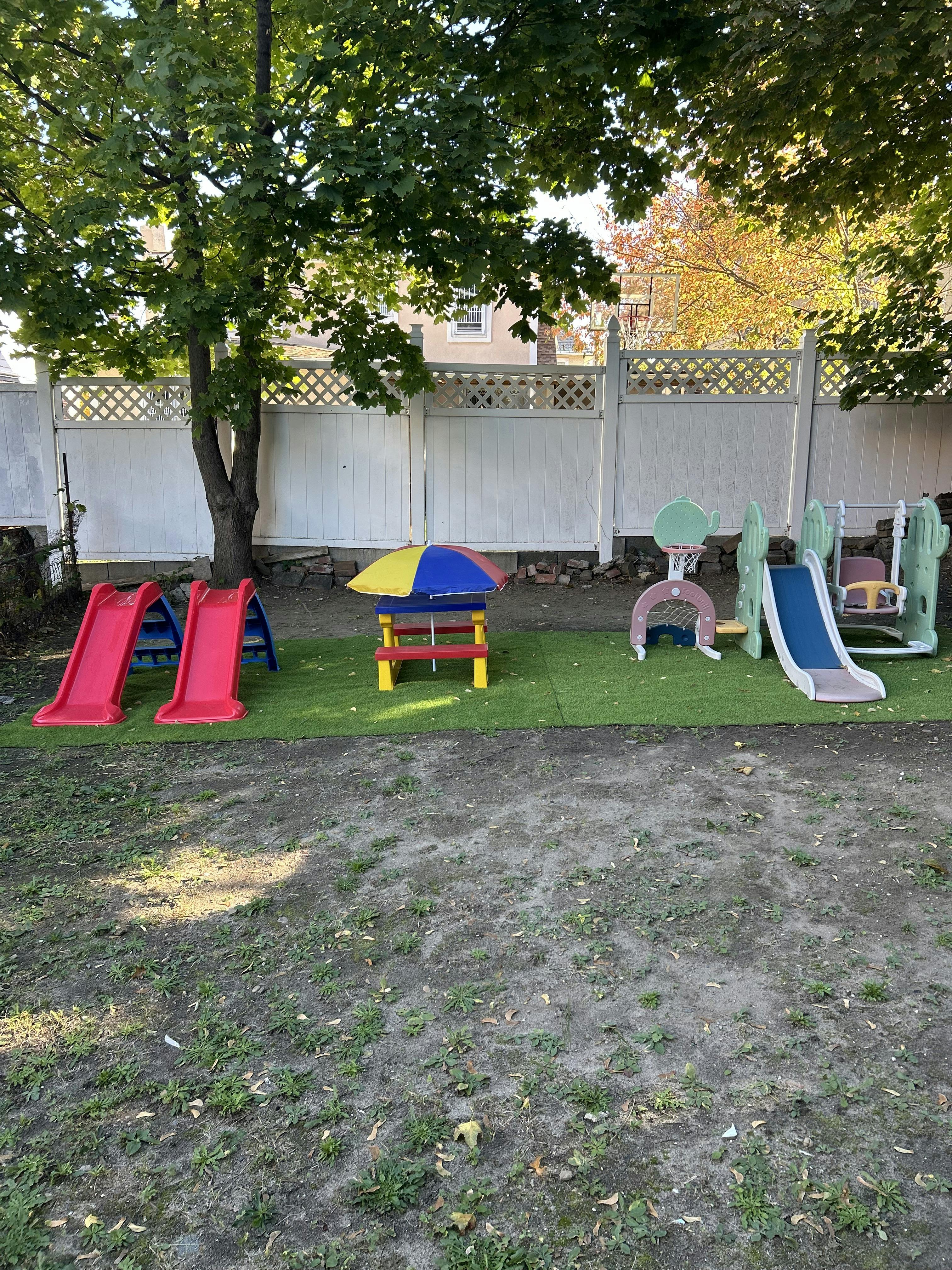 Playground with two red slides, a colorful picnic table, a blue slide, and swing