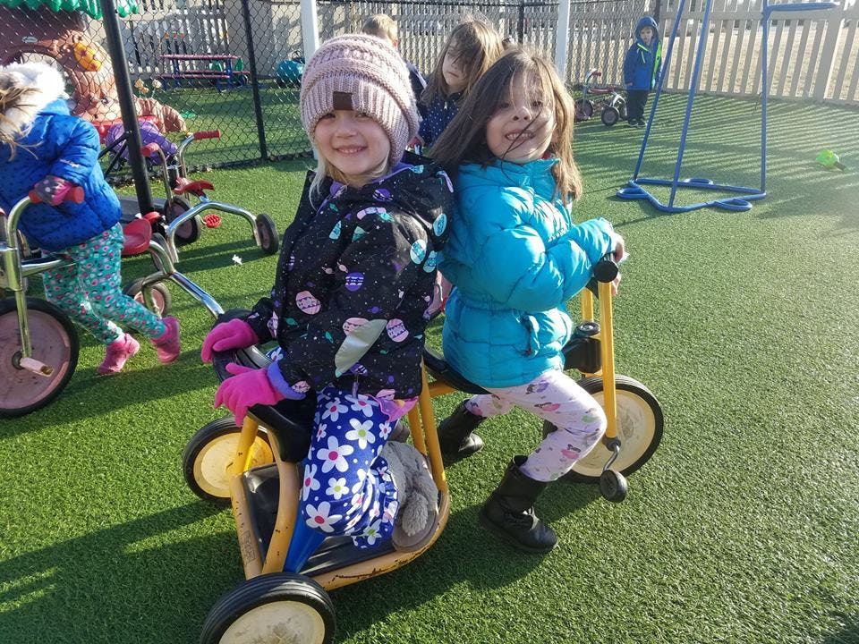 Two children on tricycles on a playground