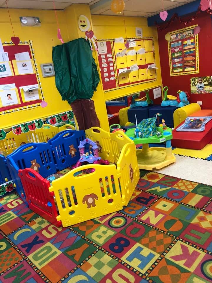Colorful playpen and activity center in a bright room with alphabet carpet