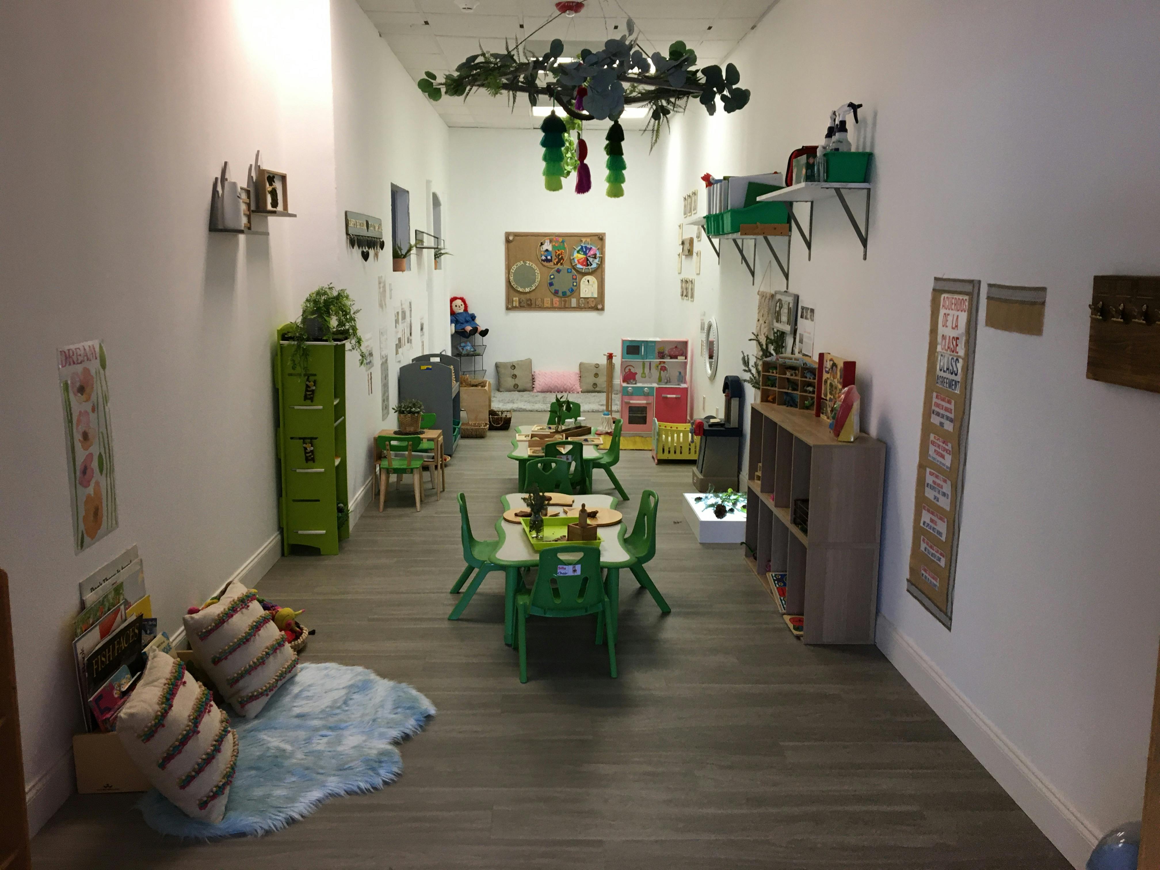 Classroom with small green tables and chairs, shelves, and wall decorations